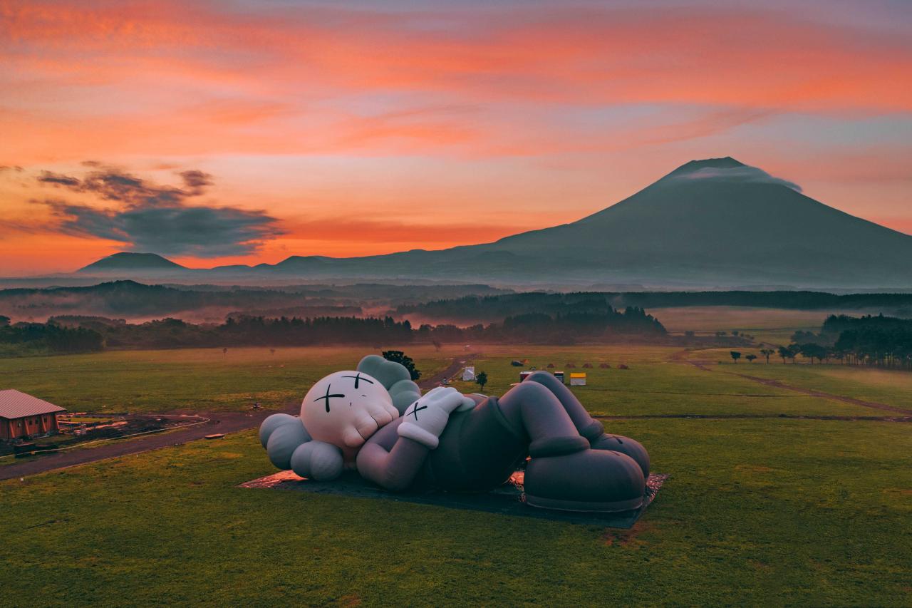 《KAWS:HOLIDAY》第四站選址日本的富士山。總長40米的全新巨型雕塑躺在遼闊草原，以悠閒的姿態凝望富士山。